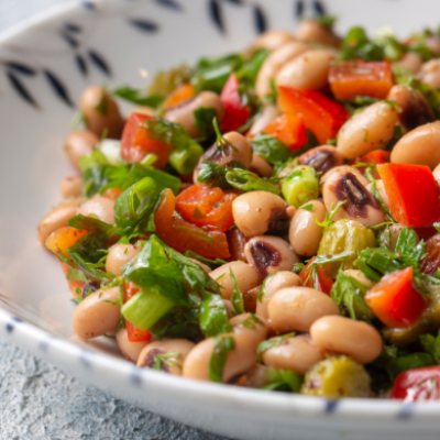 Ensalada fría de legumbres con alubias, pimiento rojo, verduras y hierbas frescas en un cuenco